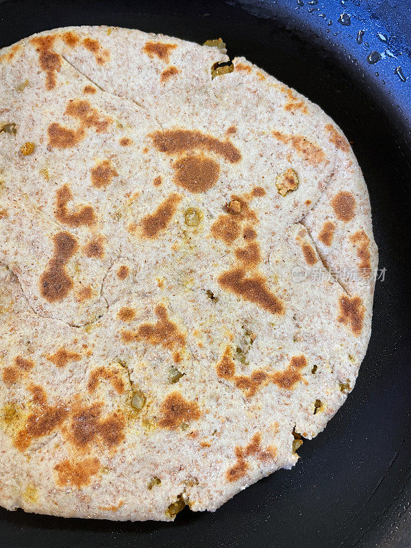 不粘锅里装着自制的gobi aloo paratha，塞满了香料土豆、花椰菜和洋葱的咸味面包，在平底锅里煎，高架视野